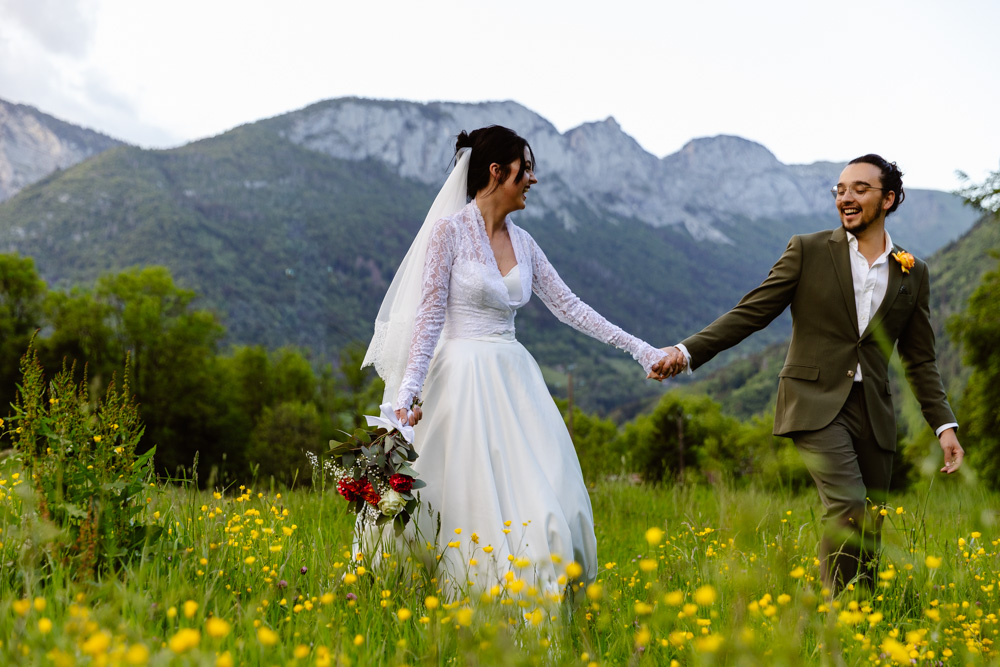 Bride and groom walking in a meadow of flowers after the ceremony